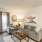 Spacious and well lit living room with wood flooring, large windows and open access to the kitchen